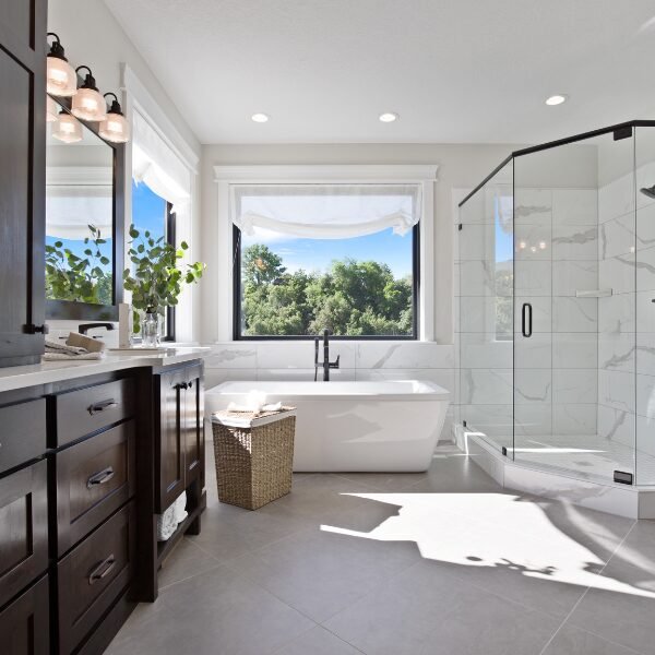 Bathroom Remodel Matthews, NC: A master bathroom showcasing modern luxury with a large glass shower and freestanding tub beneath expansive windows.